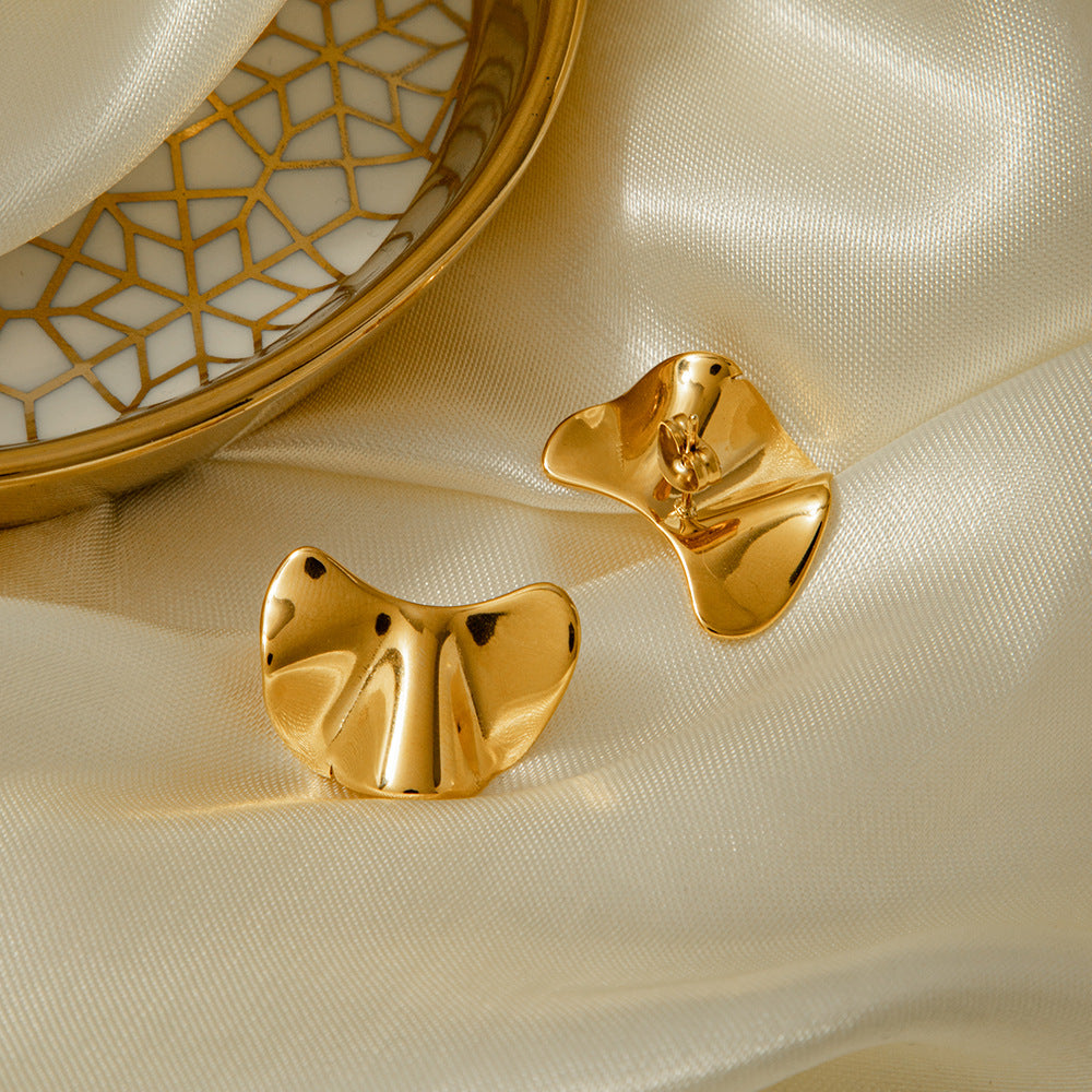 une paire de boucles d'oreilles en or posées sur un tissu blanc