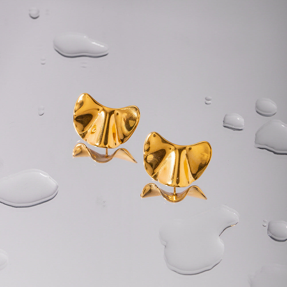 une paire de boucles d'oreilles en or sur une surface blanche