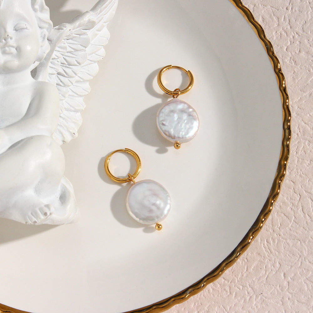 une assiette blanche surmontée de deux boucles d'oreilles et d'une statue