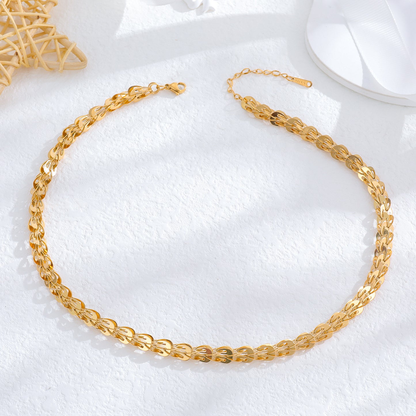 un gros plan d'un collier en or sur une surface blanche