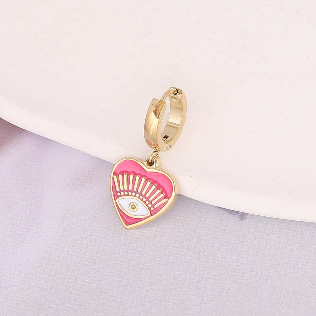 un bijou en or avec un cœur rose et un œil