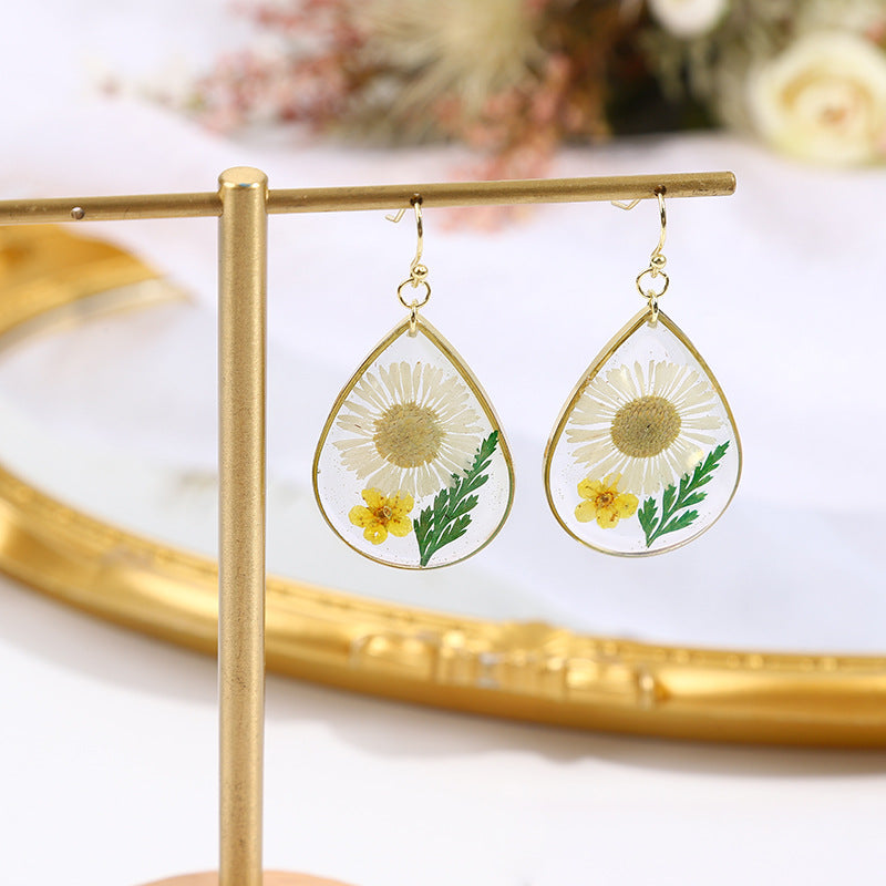 une paire de boucles d'oreilles pissenlit avec des fleurs peintes dessus