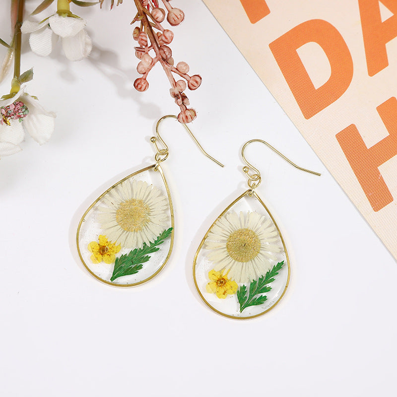 une paire de boucles d'oreilles pissenlit avec une fleur de pissenlit peinte dessus