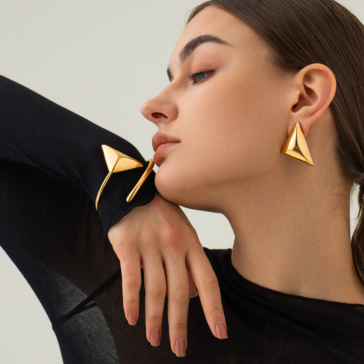 une femme portant une chemise noire et des boucles d'oreilles en or