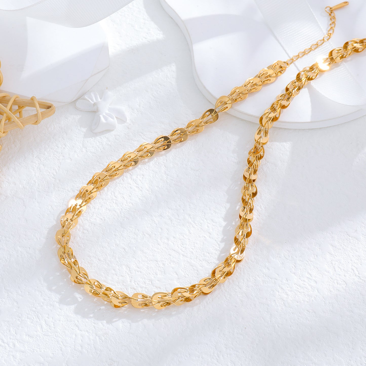 un collier en or et une assiette blanche sur une surface blanche