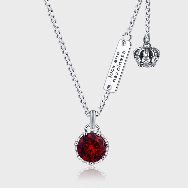 un collier avec une couronne et une pierre rouge