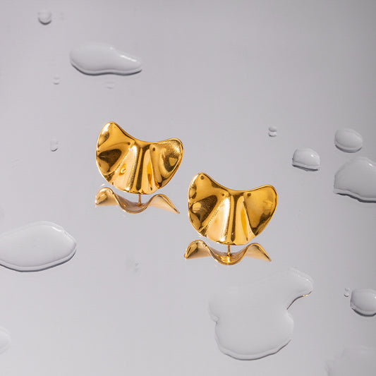 une paire de boucles d'oreilles en or sur une surface blanche