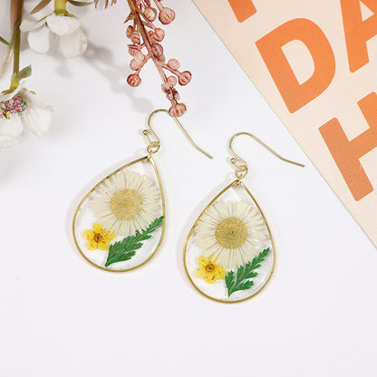 une paire de boucles d'oreilles pissenlit avec une fleur de pissenlit peinte dessus