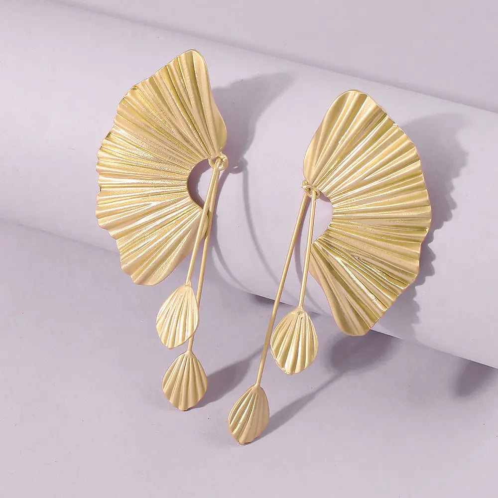 une paire de boucles d'oreilles en or sur une surface blanche