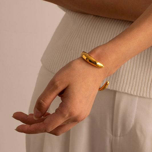 une femme portant un bracelet en or et un haut blanc