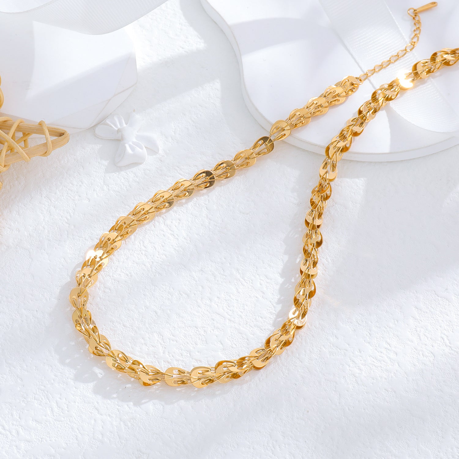 un collier en or et une assiette blanche sur une surface blanche