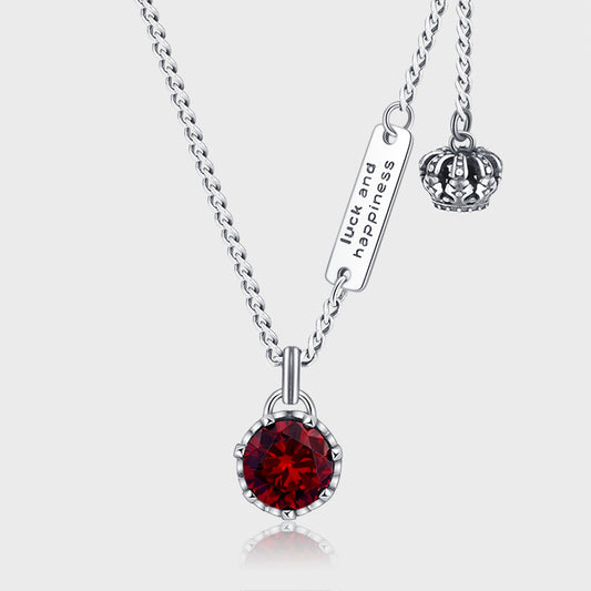 un collier avec une couronne et une pierre rouge